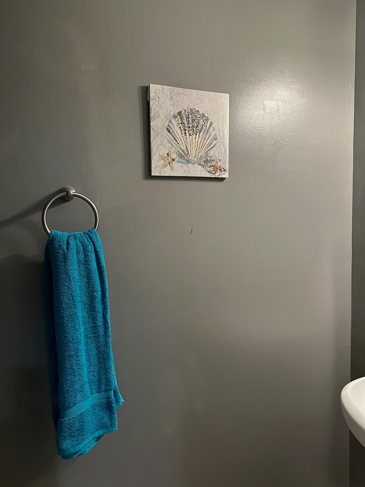 Gray bathroom wall with towel and shell art