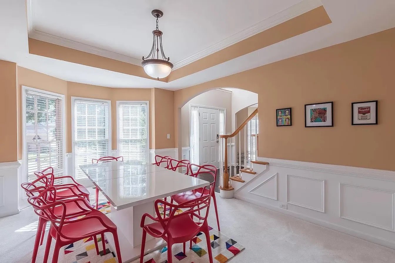Dining room with tan walls and red chairs